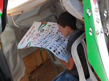 This boy looks at photos of some of those who are being detained in Israeli prisons. His father is one of them. Like many children he has been denied the right to visit his father.